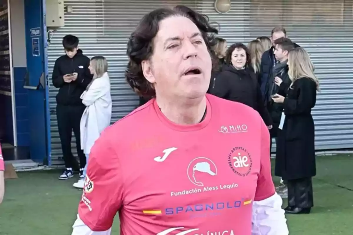 Pipi Estrada con camiseta rosa de la Fundación Aless Lequio está en un evento al aire libre con varias personas al fondo. Pipi Estrada con camiseta rosa de la Fundación Aless Lequio está en un evento al aire libre con varias personas al fondo.