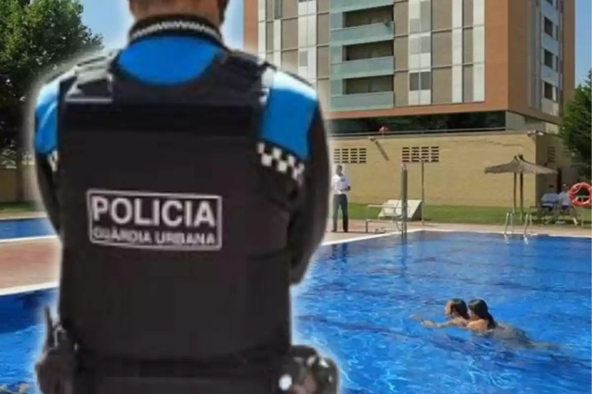 Un policía de la Guardia Urbana observa una piscina en la que nadan dos personas, con un edificio de apartamentos al fondo.