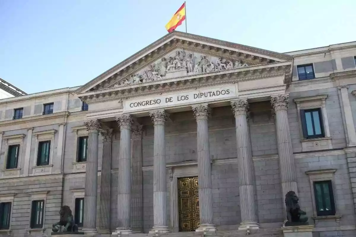 Plano general del Congreso de los Diputados de día con la bandera española ondeando