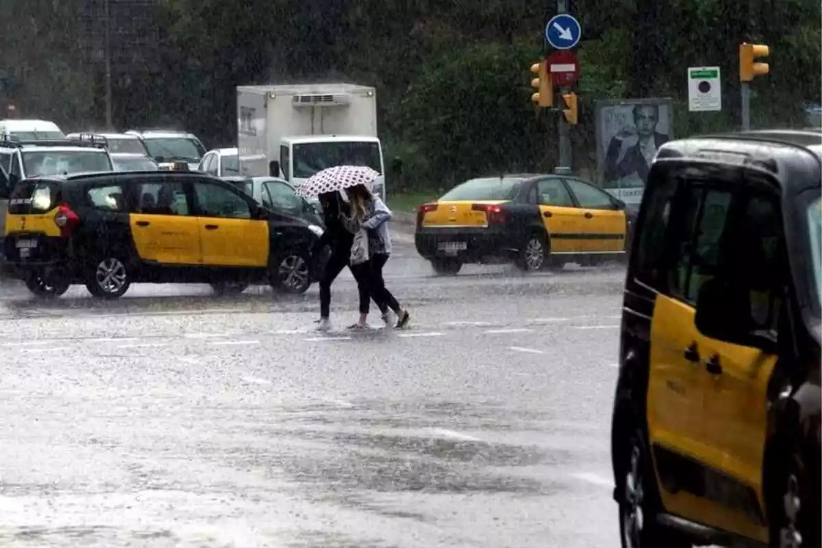 Imagen de dos personas bajo un paraguas en medio de Via Laietana, en Barcelona
