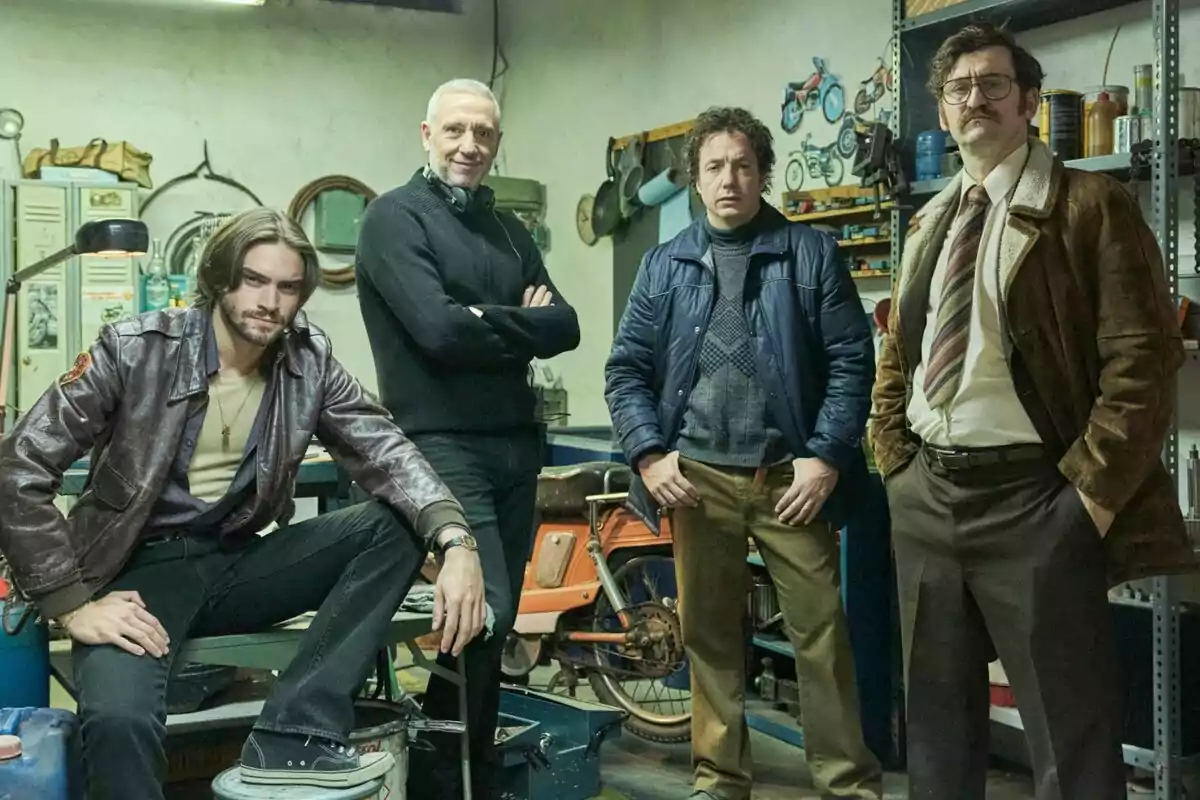Raúl Arévalo, Vito Sanz, Agustín Otón y otro hombre posan en un taller mecánico rodeados de herramientas y una motocicleta en el rodaje de Por Cien Millones.