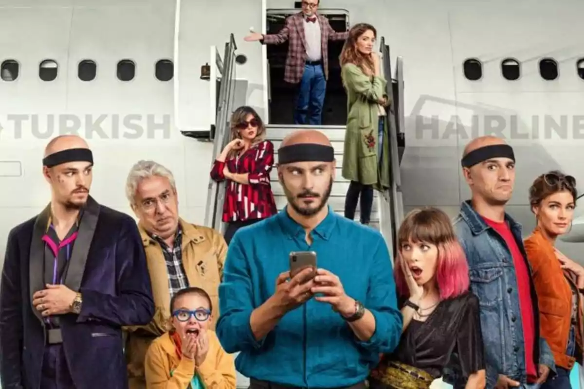 Un grupo de personas de pie frente a un avión, algunas con expresiones sorprendidas y otras con actitud relajada, mientras un hombre en el centro sostiene un teléfono móvil en la película Por los pelos.