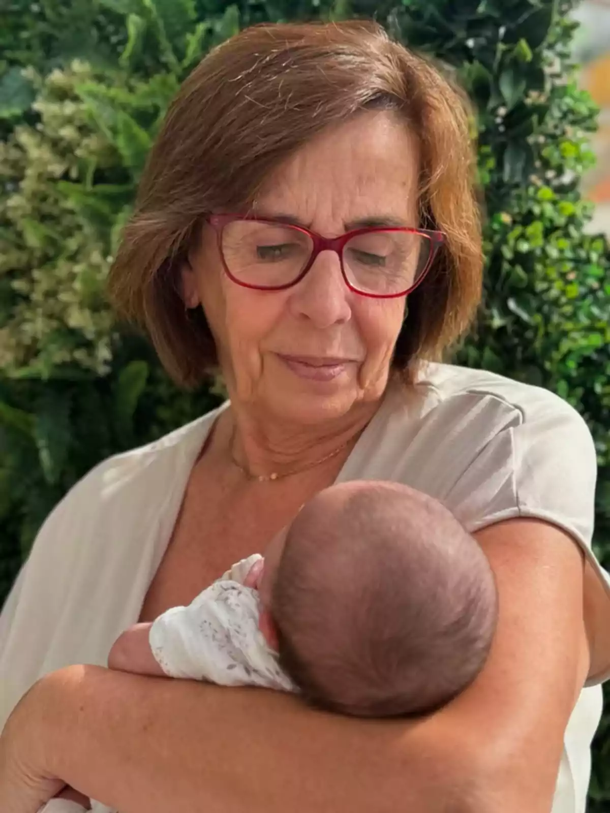 Mercedes Bernal sostiene en brazos a Alma mientras lo mira con ternura rodeada de plantas verdes Mercedes Bernal sostiene en brazos a Alma mientras lo mira con ternura rodeada de plantas verdes