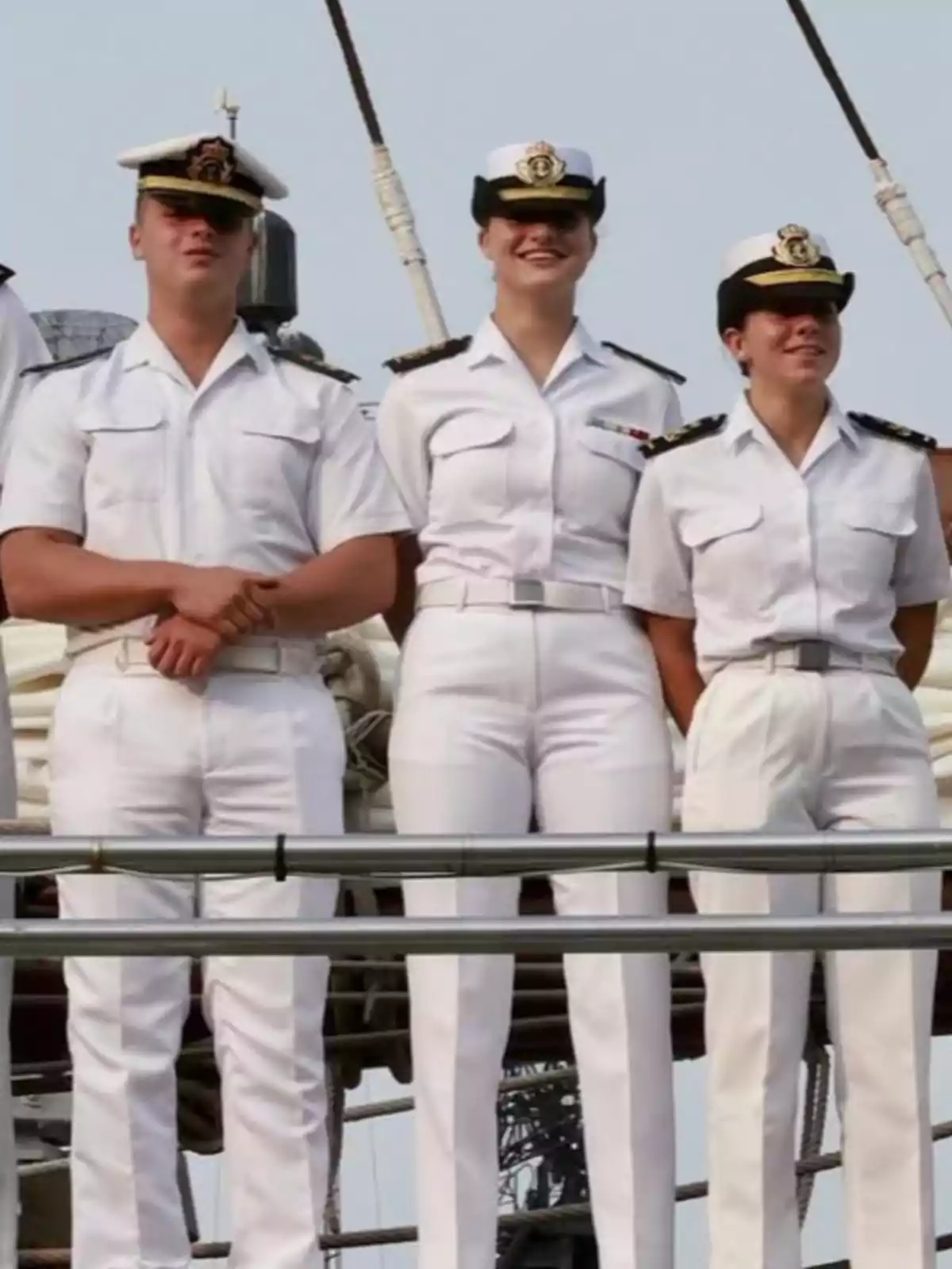La princesa Leonor y dos compañeros con uniforme blanco de marina posan de pie sobre la cubierta de un barco La princesa Leonor y dos compañeros con uniforme blanco de marina posan de pie sobre la cubierta de un barco