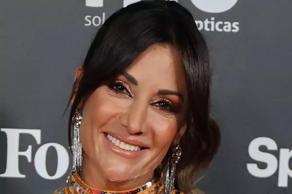 Nagore Robles sonriente con cabello oscuro y aretes largos posando frente a un fondo con logotipos.