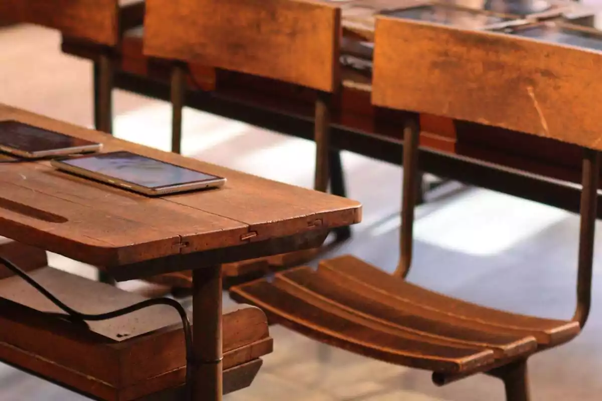 Primer plano de una mesa con sillas de madera con dos tablets encima