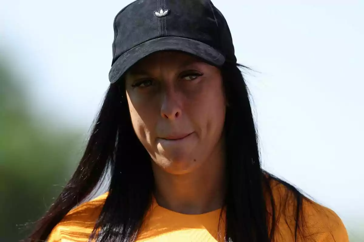 Jenni Hermoso con gorra negra y camiseta amarilla en un entorno al aire libre.