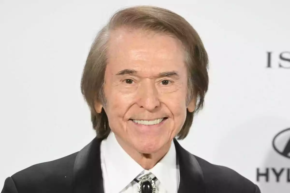 Raphael sonriente con traje y corbata en un evento formal.