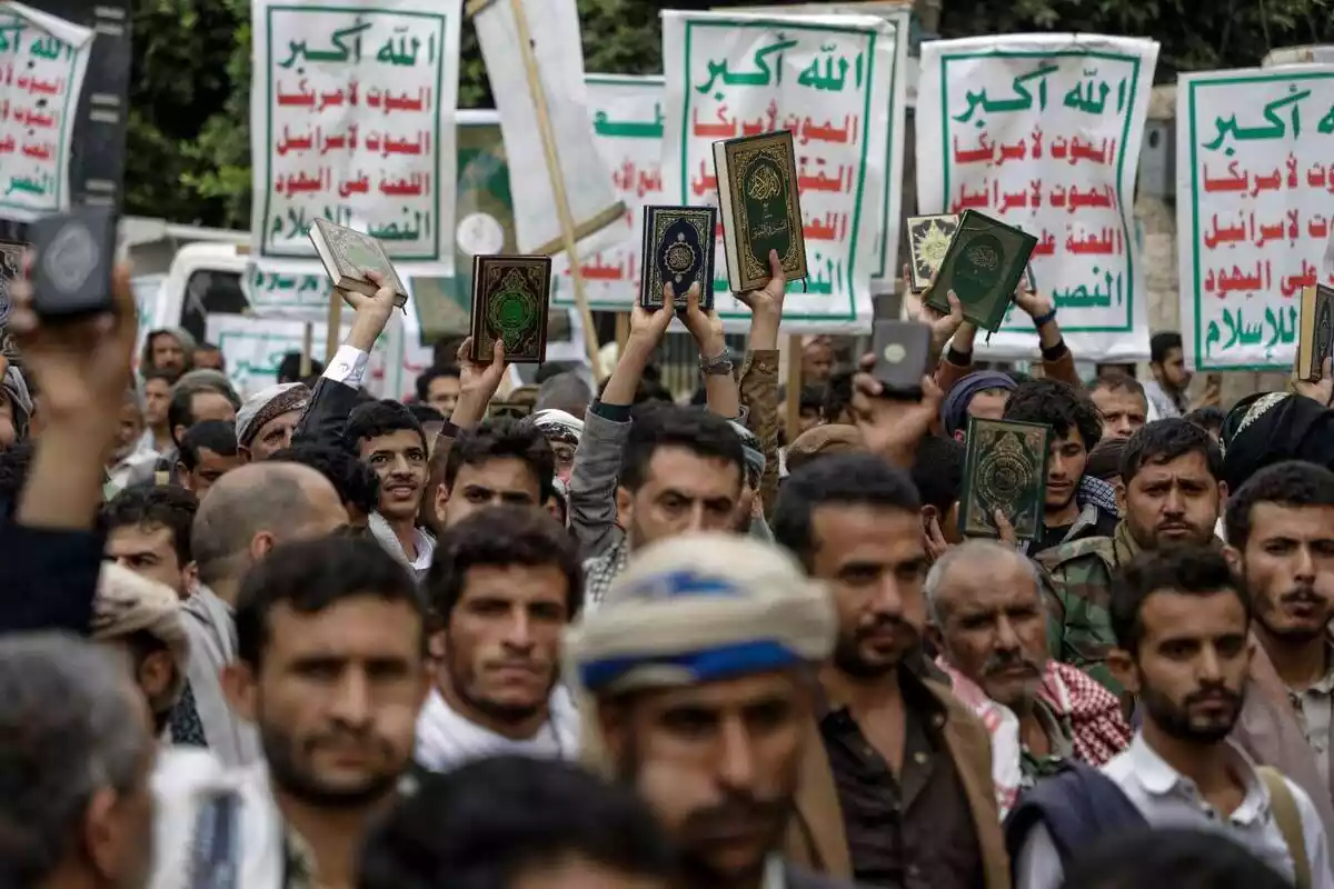 Varios manifestantes en Yemen protestan por la quema de un Corán en Suecia levantando un Corán y varias pancartas con letras verdes y rojas en árabe