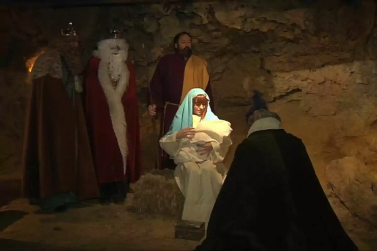 Una representación del nacimiento de Jesús con María sosteniendo al niño y los Reyes Magos presentes en un entorno de cueva.