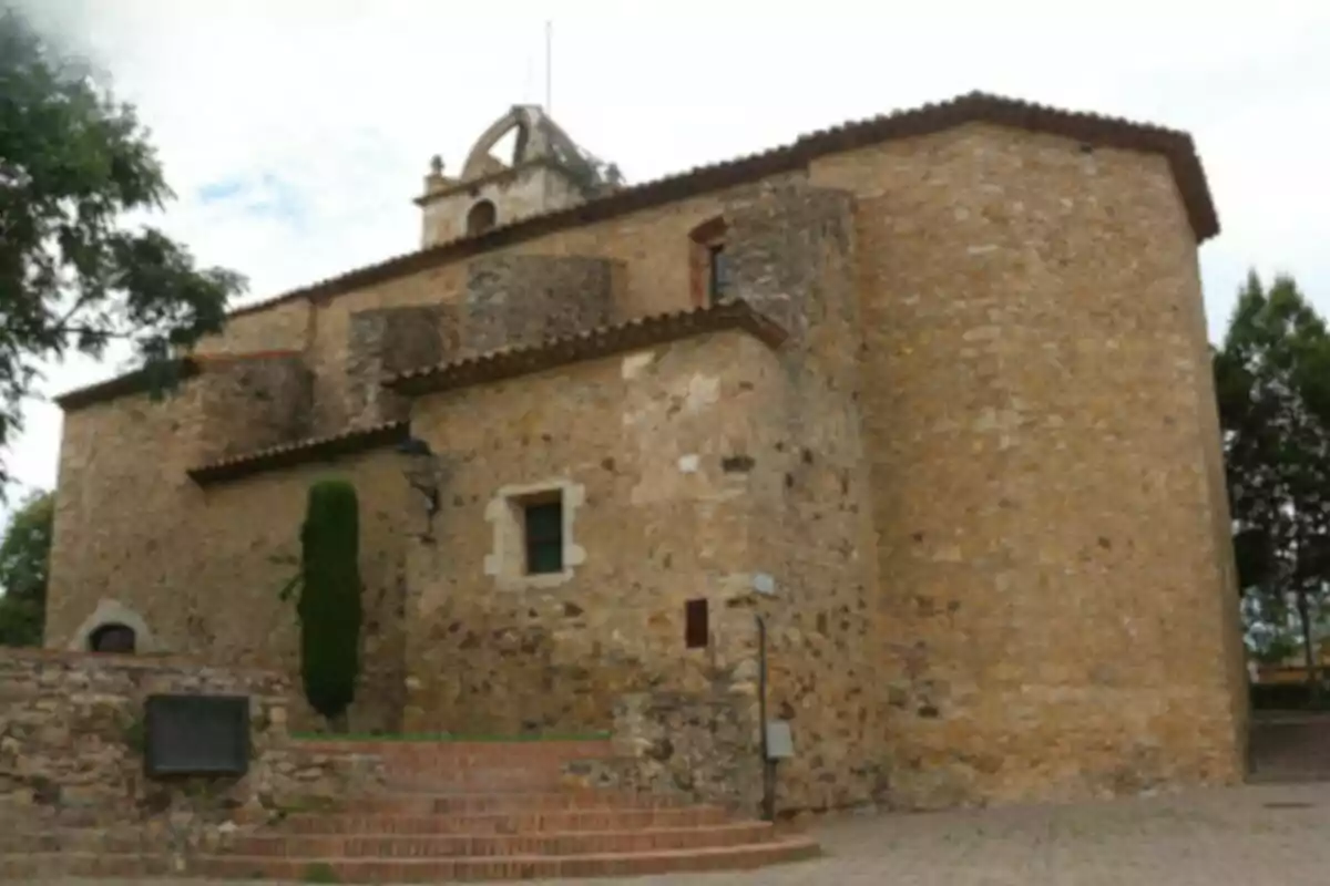 Una iglesia de piedra con un campanario pequeño y un árbol al lado en un entorno rural. Una iglesia de piedra con un campanario pequeño y un árbol al lado en un entorno rural.