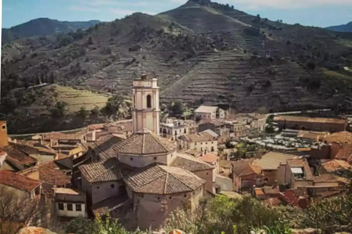 Vista panorámica de un pueblo con una iglesia en el centro y montañas al fondo. Vista panorámica de un pueblo con una iglesia en el centro y montañas al fondo.