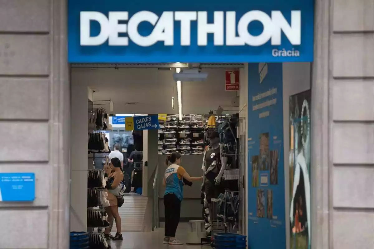 Imagen del exterior de una tienda de Decathlon en Barcelona con una dependienta colocando productos en el interior