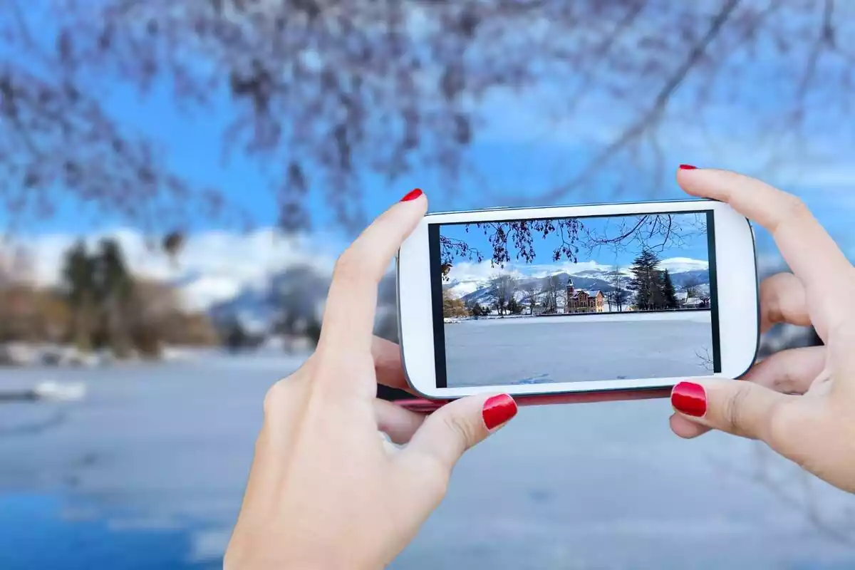 Montaje fotográfico de un teléfono móvil haciendo una foto en el lago de Puigcerdà