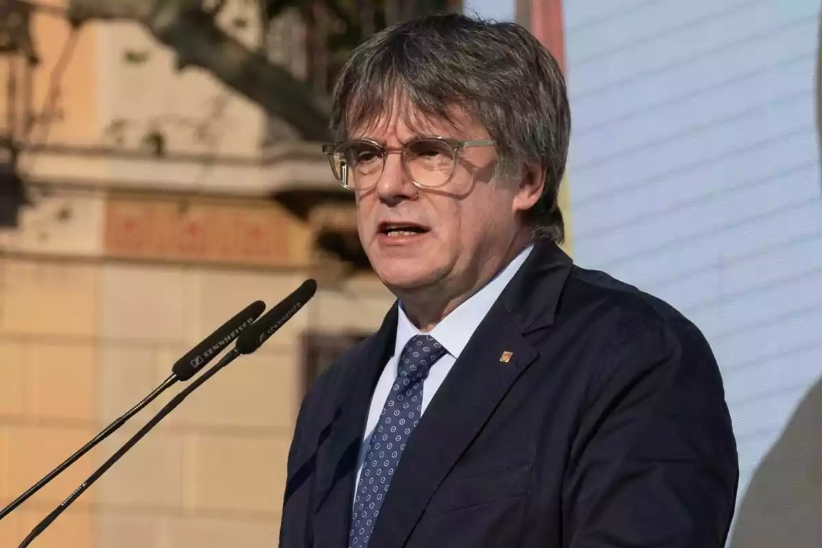 Carles Puigdemont con traje oscuro hablando frente a un micrófono.