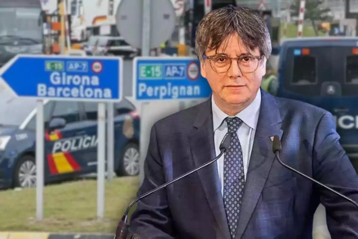 Hombre con traje y gafas frente a señales de tráfico que indican direcciones hacia Girona, Barcelona y Perpiñán, con coches de policía en el fondo.