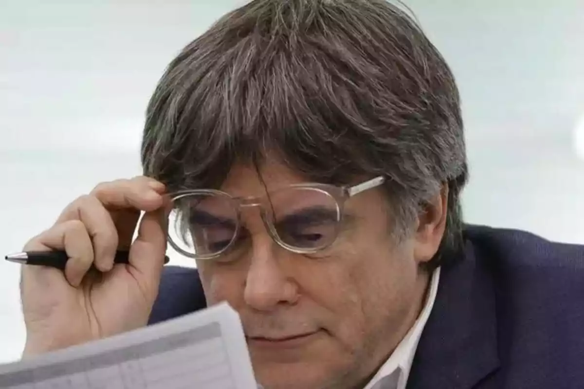 Un hombre con gafas revisa un documento mientras sostiene un bolígrafo. Un hombre con gafas revisa un documento mientras sostiene un bolígrafo.