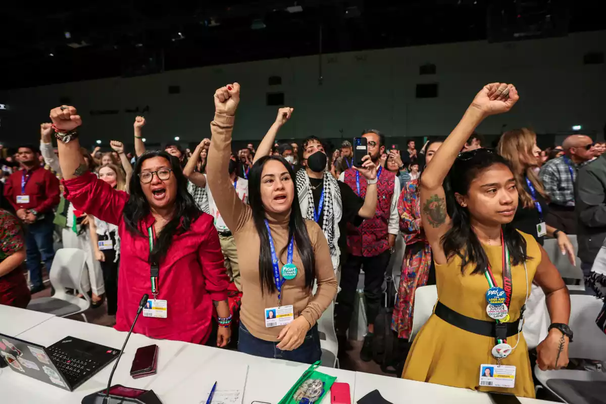 Grupo de participantes de la COP28 con el puño arriba y uno de ellos haciendo una fotografía con el teléfono Grupo de participantes de la COP28 con el puño arriba y uno de ellos haciendo una fotografía con el teléfono