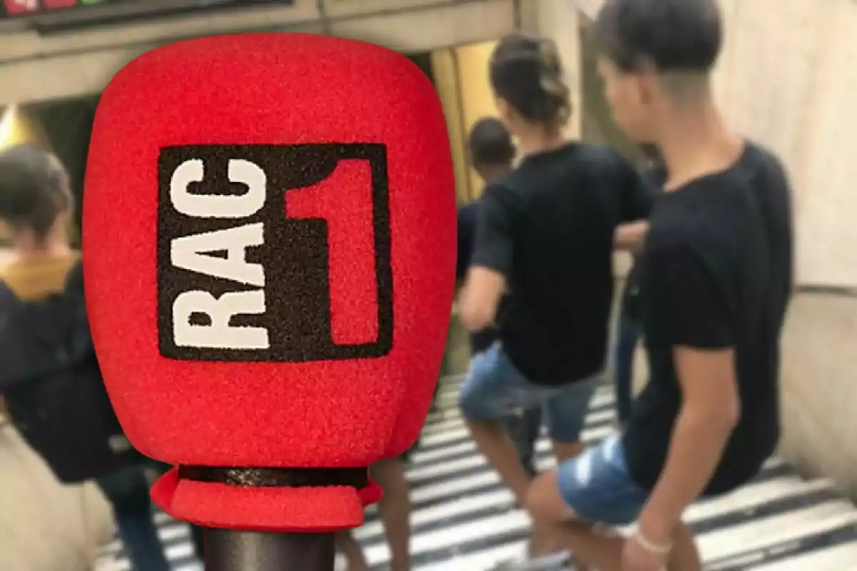 Micrófono rojo con el logo de RAC1 en primer plano y personas bajando escaleras en el fondo.