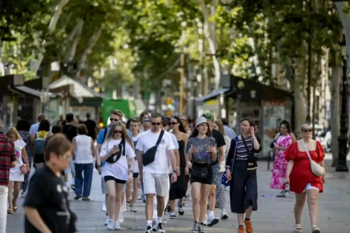 Un grupo de personas caminando por la Rambla de Barcelona en un día soleado.