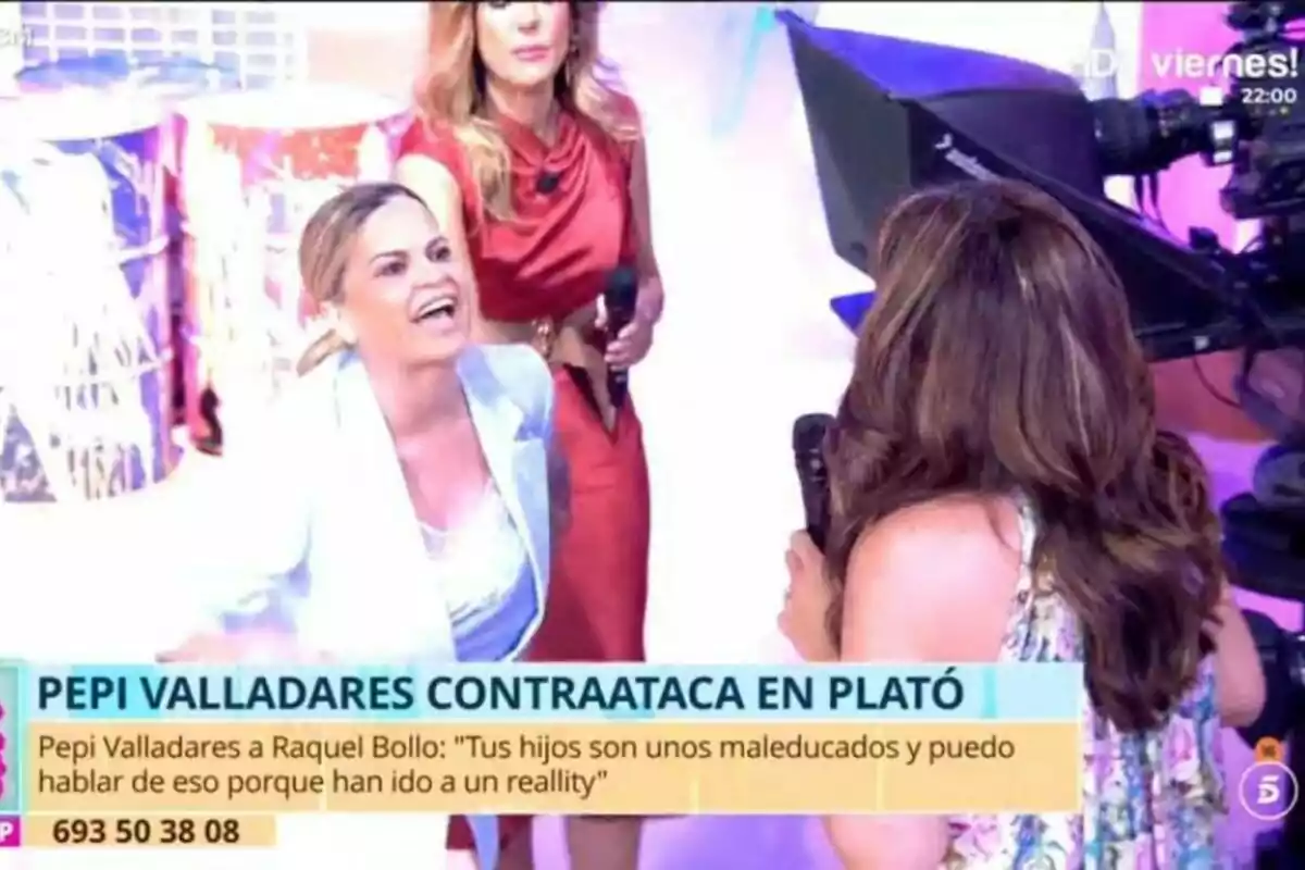En un plató de televisión de Tardear, Pepi Valladares y Raquel Bollo están interactuando de manera intensa mientras una cámara graba la escena. En un plató de televisión de Tardear, Pepi Valladares y Raquel Bollo están interactuando de manera intensa mientras una cámara graba la escena.