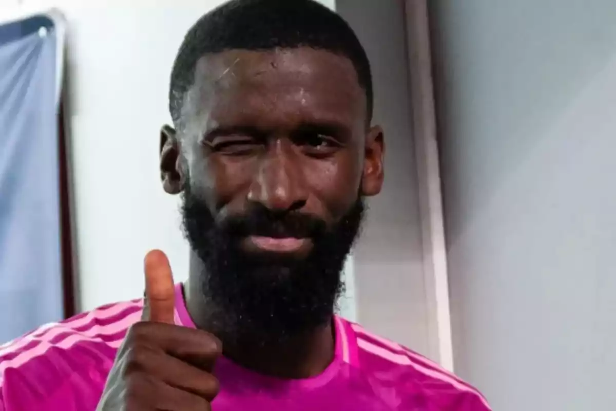 Un hombre con barba y camiseta rosa guiña un ojo y levanta el pulgar. Un hombre con barba y camiseta rosa guiña un ojo y levanta el pulgar.