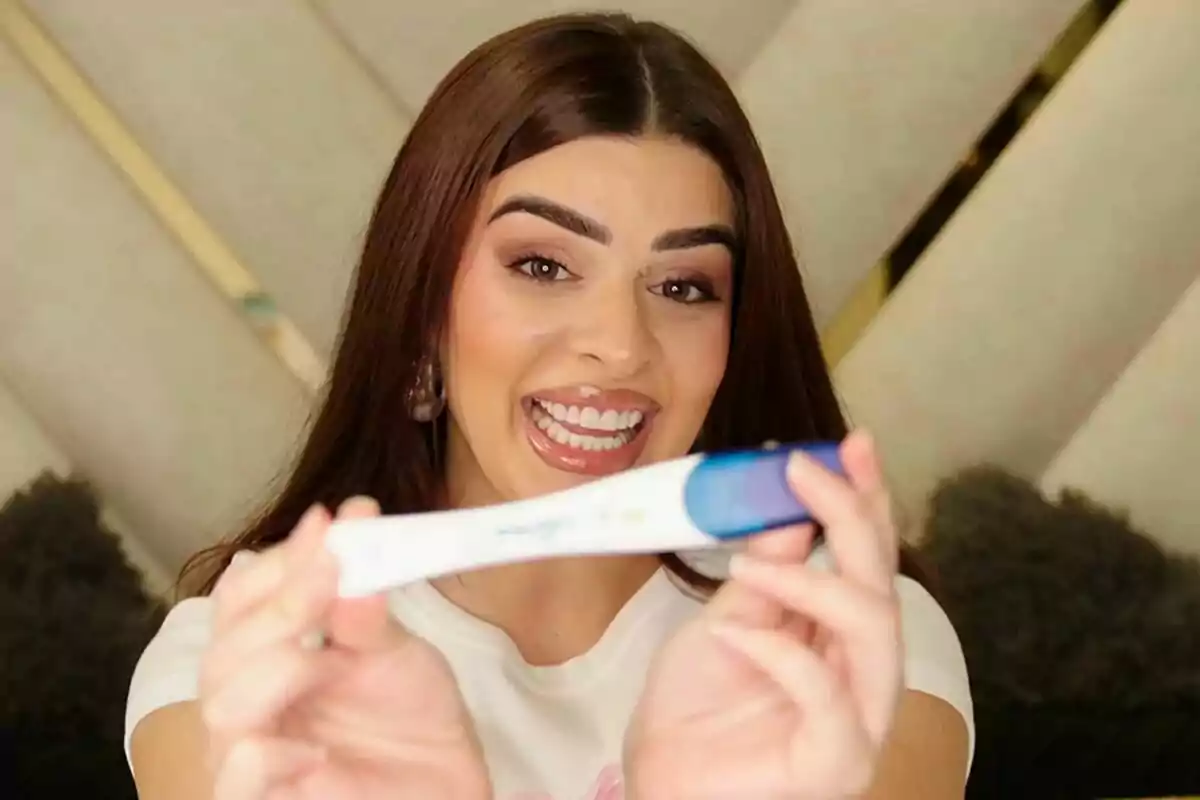 Rebeca Jiménez sonriente sostiene una prueba de embarazo frente a la cámara en Los Gipsy Kings
