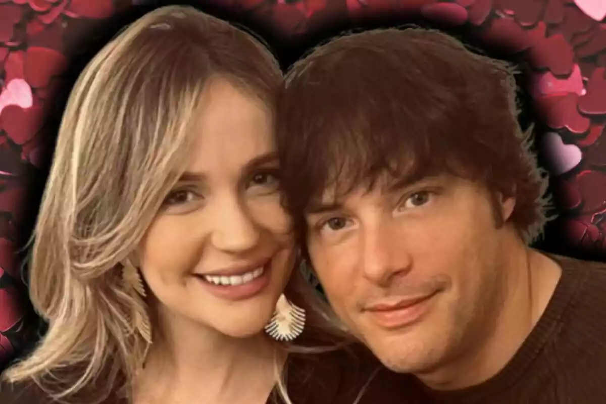 Una pareja, formada por Jordi Cruz y Rebecca Lima, sonriente posando juntos frente a un fondo de corazones rojos.