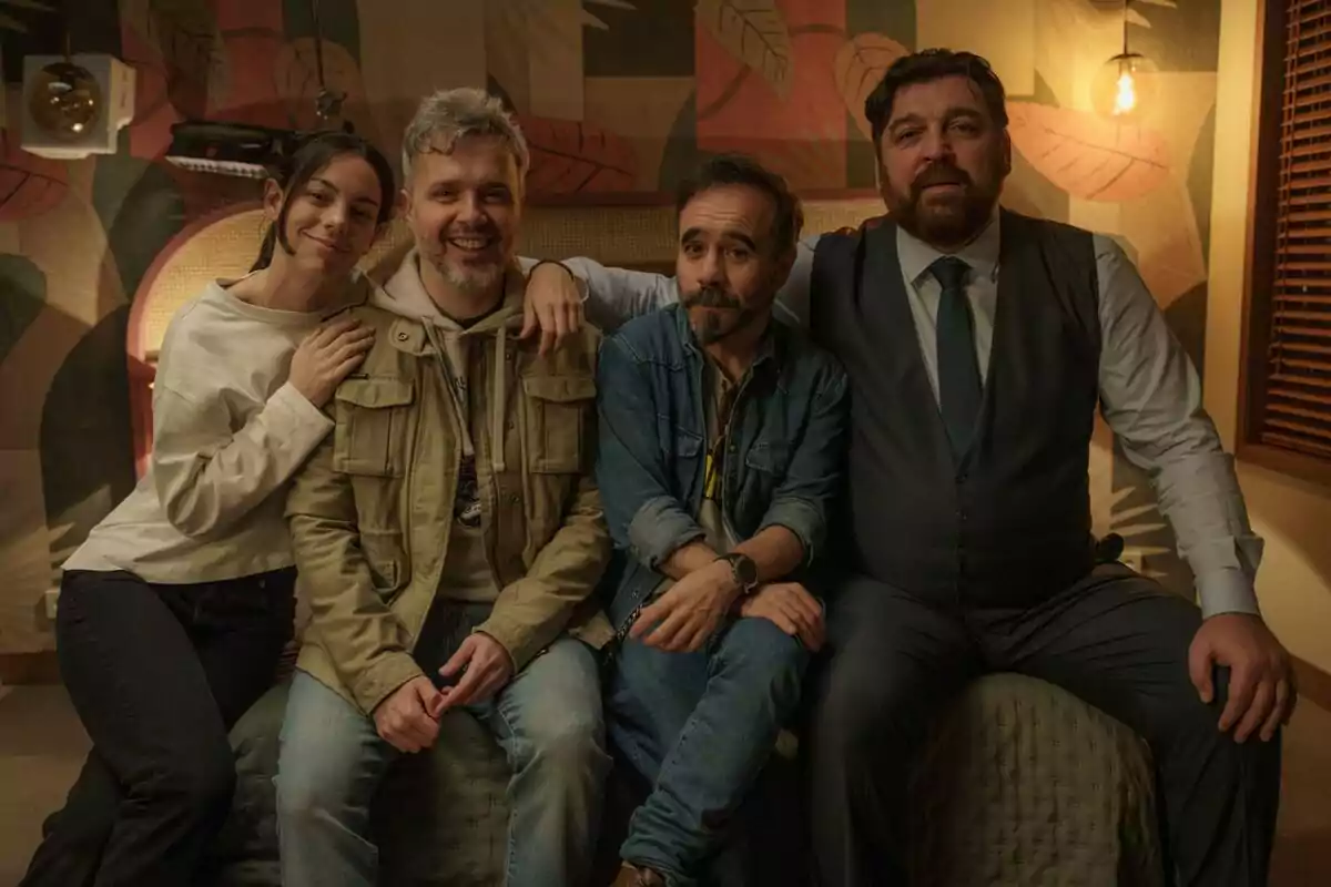 Juan Gómez-Jurado, Victoria Luengo y Hovik Keuchkerian sentadas en un sofá, sonriendo y posando para la cámara en un ambiente interior con una decoración cálida y acogedora en el inicio del rodaje de la segunda temporada de Reina Roja.