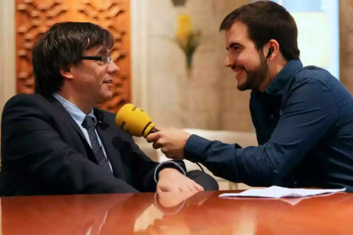 Ricard Ustrell entrevistando a Carles Puigdemont con un micrófono de Catalunya Radio en la mano, ambos sonrientes