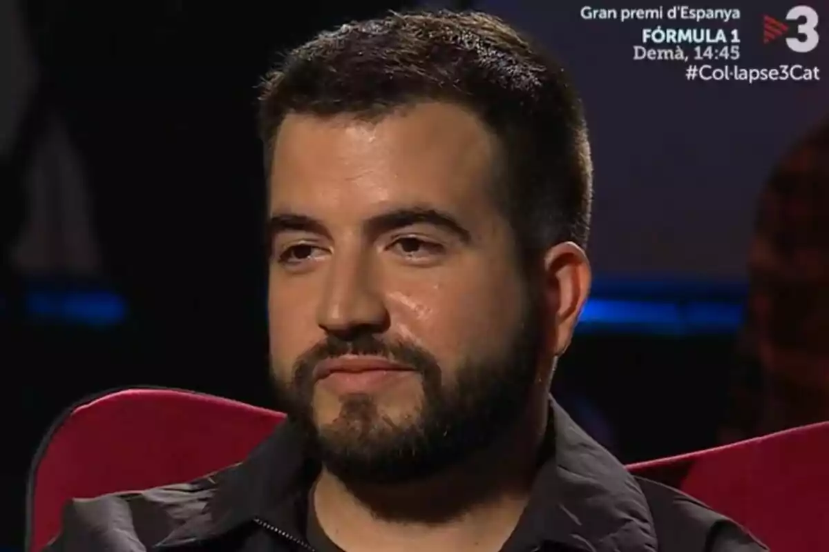 Ricard Ustrell de barba y cabello corto sentado en un sillón rojo con expresión seria en un estudio de televisión en Col·lapse de TV3