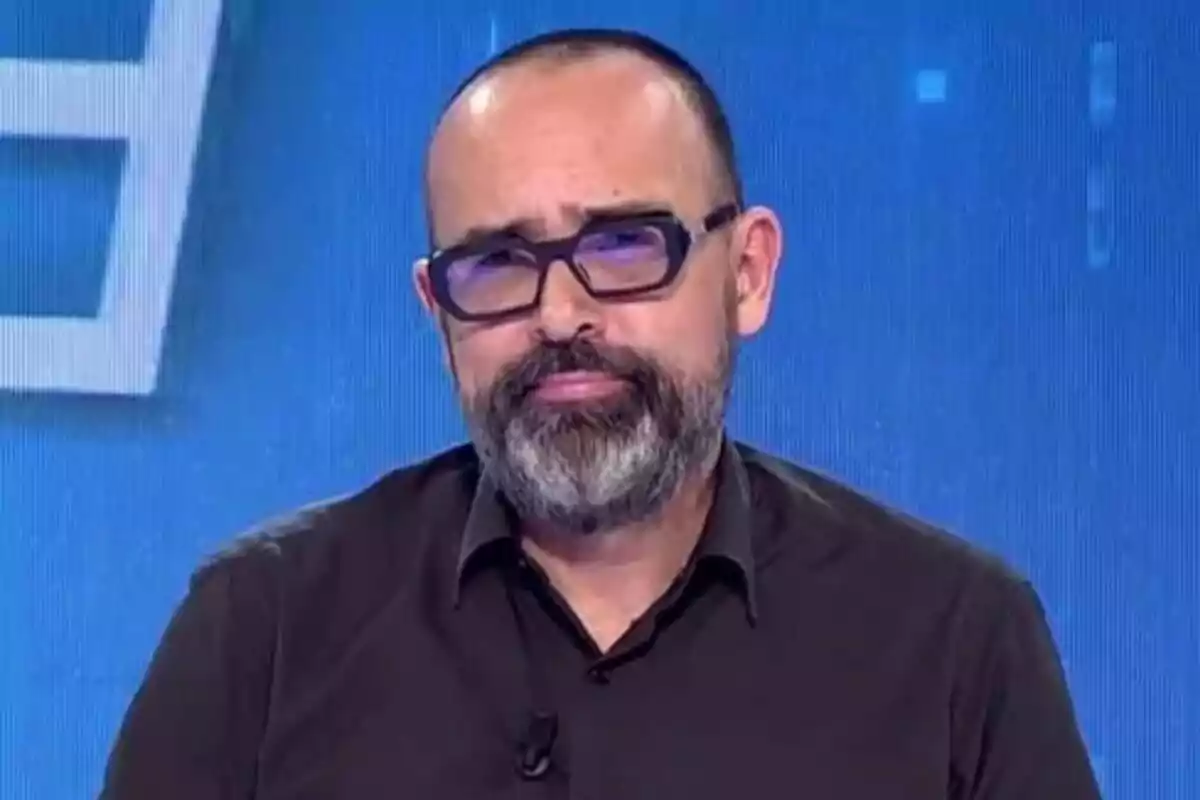 Risto Mejide con barba y gafas en Todo es Mentira con fondo azul.