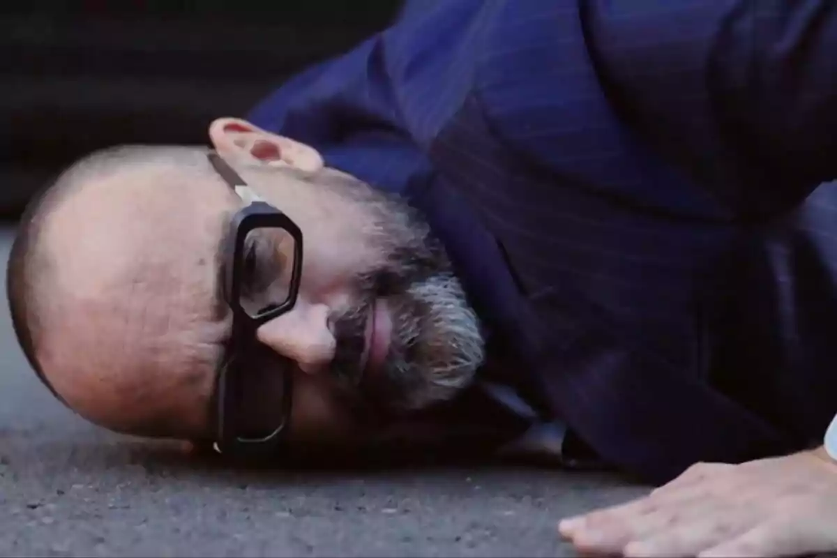 Risto Mejide con gafas y barba tumbado en el suelo con traje azul en la promo de Demos: El Gran Sondeo