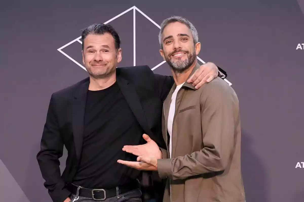 Iñaki López y Roberto Leal posando juntos y sonriendo frente a un fondo gris con un diseño geométrico blanco en la presentación de López y Leal contra el canal.