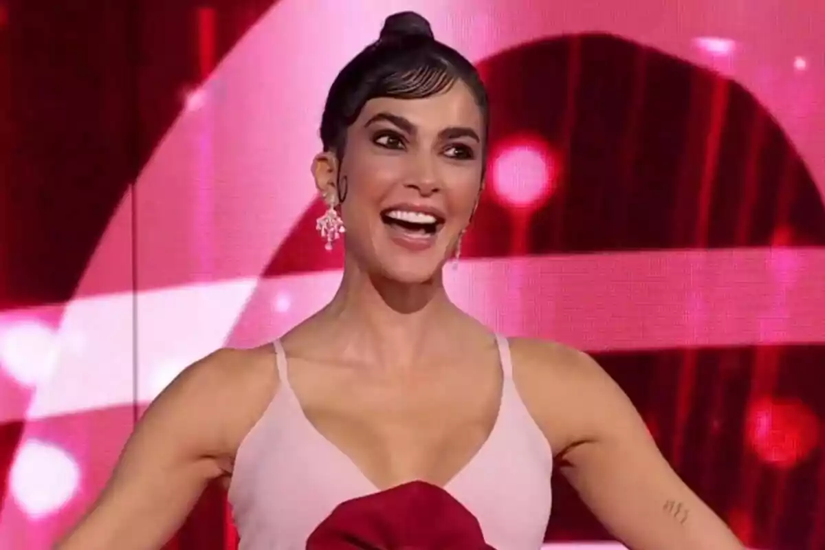 Rocío Muñoz sonriente con un vestido rosa y fondo rojo con luces en La Bien Cantá.