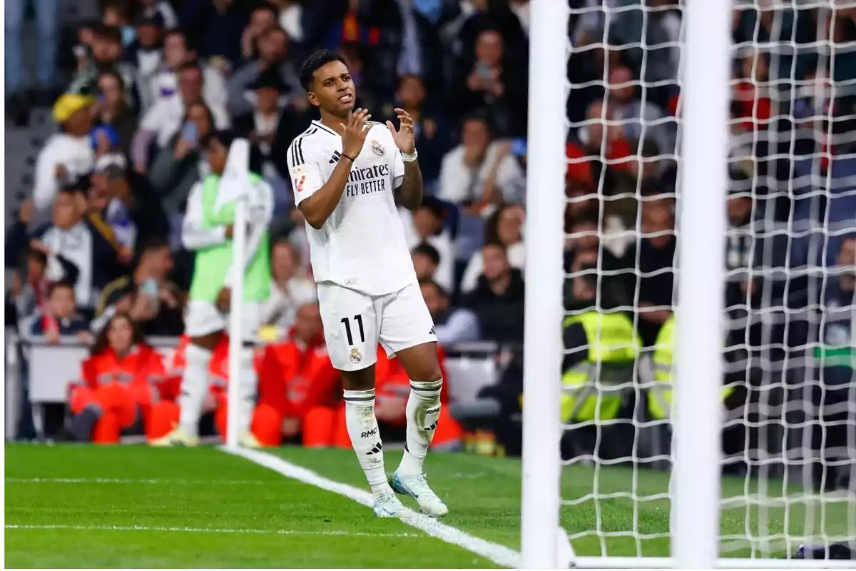 Futbolista del Real Madrid con el número 11 muestra frustración frente a la portería durante un partido, con aficionados y personal en el fondo. Futbolista del Real Madrid con el número 11 muestra frustración frente a la portería durante un partido, con aficionados y personal en el fondo.
