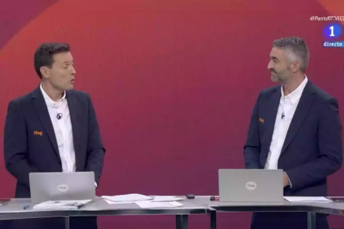 Fotografía de Roi Groba y Alberto Freile en RTVE conversan en un set con fondo rojo, cada uno frente a una computadora portátil durante la retransmisión de los Juegos Olímpicos