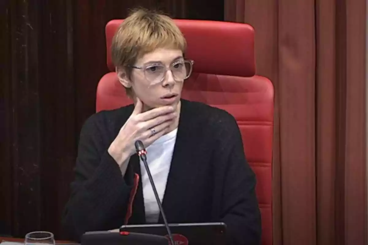 Plano medio de Rosa Romà en sentada en la tribuna de la comisión de control de la Corpo en el Parlament de Catalunya, tocándose la barbilla