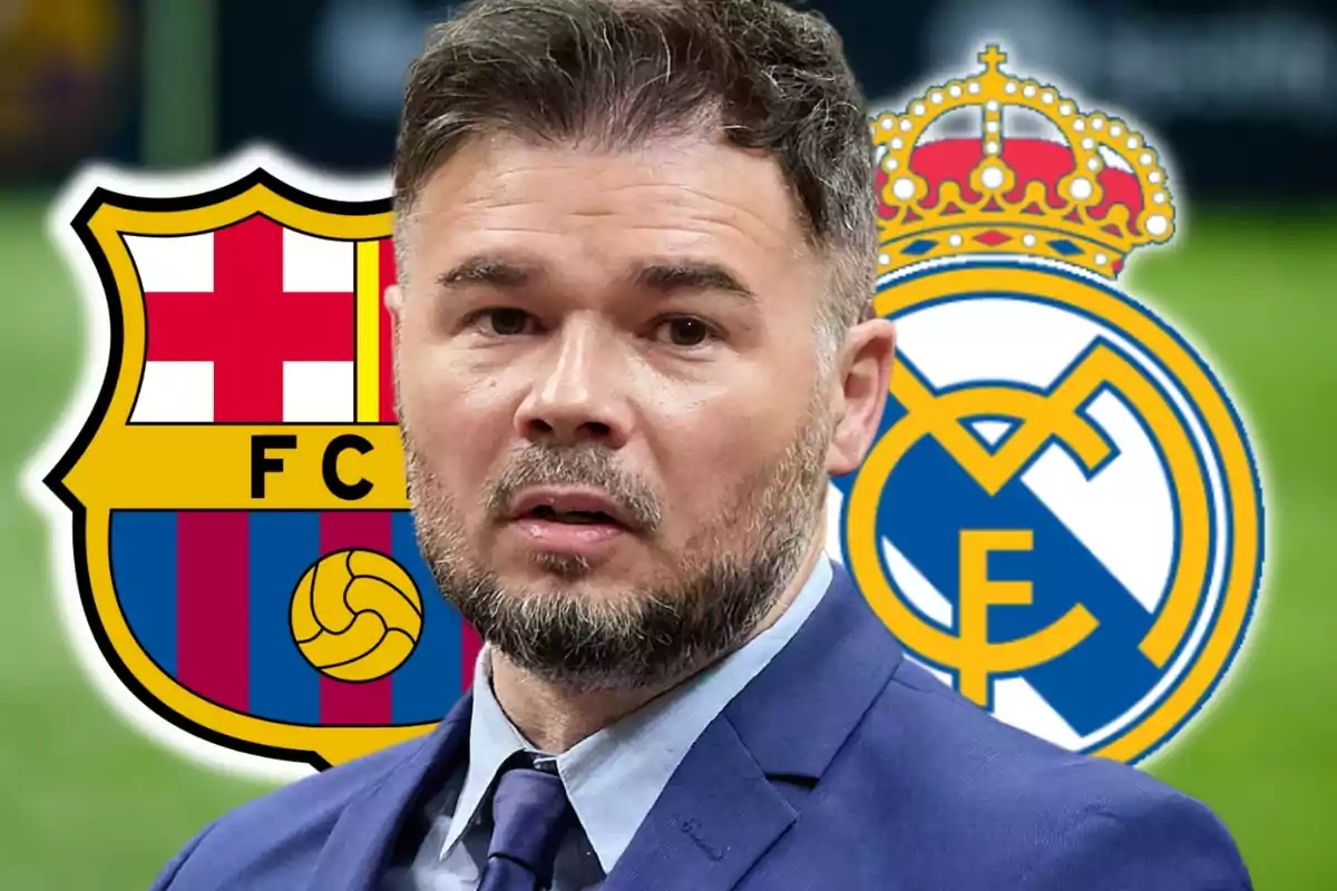 Un hombre con barba y traje está frente a los escudos del FC Barcelona y el Real Madrid.