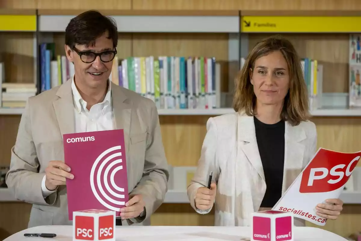 Dos personas sostienen documentos de los partidos "comuns" y "PSC" en un entorno de biblioteca.