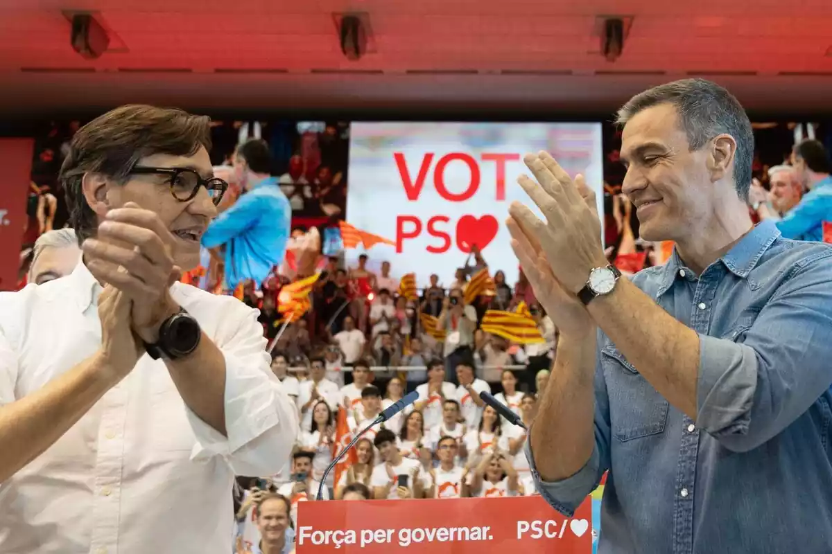 Salvador Illa y Pedro Sánchez mirándose a los ojos sonrientes en un acto del PSC