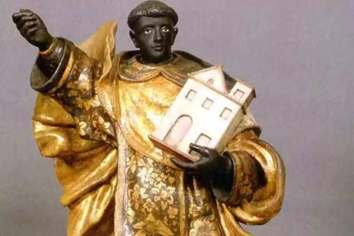 Una estatua de un santo con túnica dorada sosteniendo un modelo de edificio en su mano izquierda. Una estatua de un santo con túnica dorada sosteniendo un modelo de edificio en su mano izquierda.