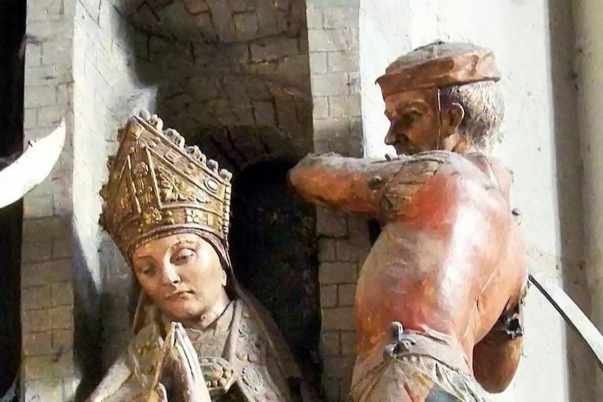 Escultura de un hombre con una espada levantada detrás de una figura religiosa con mitra. Escultura de un hombre con una espada levantada detrás de una figura religiosa con mitra.