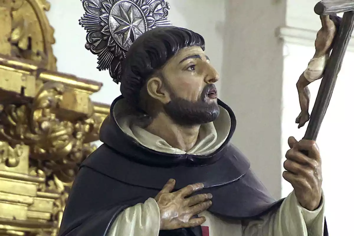 Una estatua religiosa de un santo con un halo decorativo sosteniendo un crucifijo en un entorno de iglesia con detalles dorados. Una estatua religiosa de un santo con un halo decorativo sosteniendo un crucifijo en un entorno de iglesia con detalles dorados.