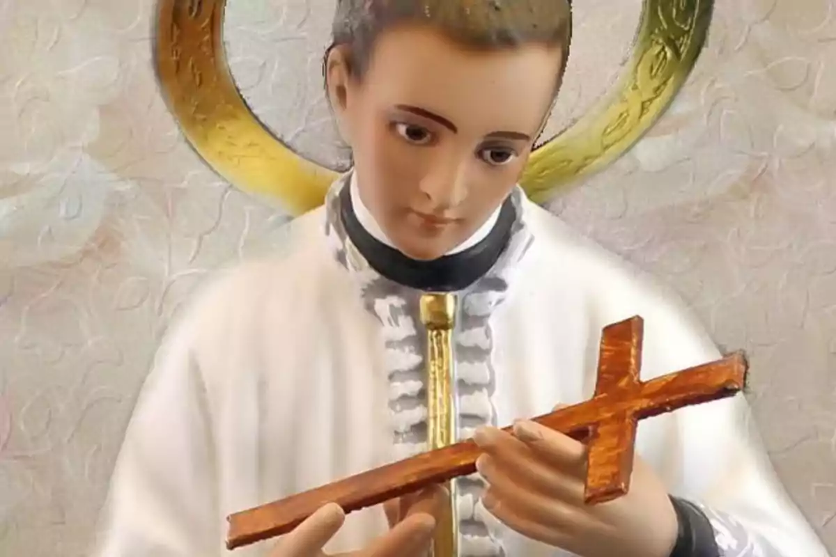 Escultura religiosa de un joven santo con aureola dorada sosteniendo una cruz de madera