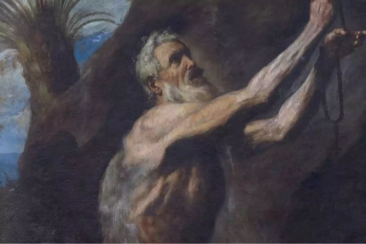 Un hombre anciano de barba blanca y torso desnudo sostiene un rosario con ambas manos extendidas hacia arriba en un entorno oscuro y rocoso. Un hombre anciano de barba blanca y torso desnudo sostiene un rosario con ambas manos extendidas hacia arriba en un entorno oscuro y rocoso.