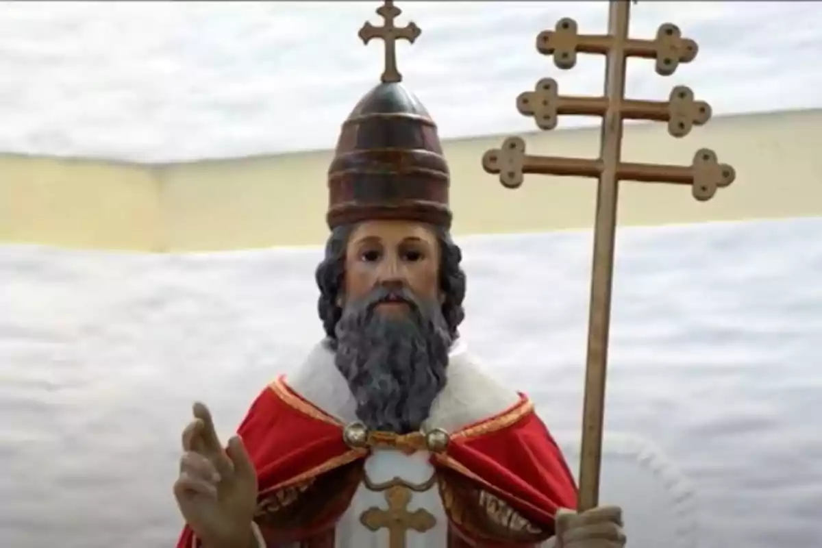 Escultura religiosa de un hombre con barba y vestimenta papal sosteniendo un báculo con varias cruces