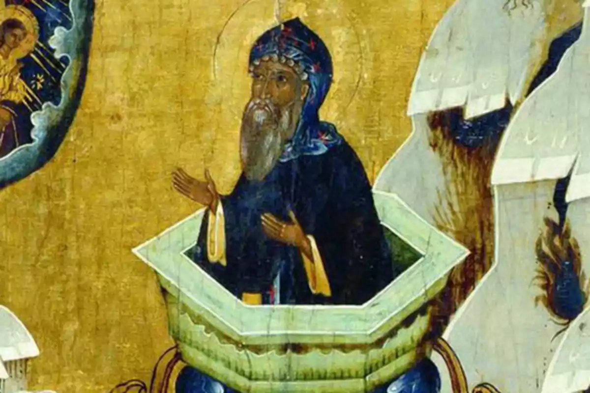 Una pintura religiosa muestra a un hombre con vestimenta oscura y barba dentro de una estructura cilíndrica con las manos levantadas en actitud de oración mientras mira hacia una figura celestial en el cielo. Una pintura religiosa muestra a un hombre con vestimenta oscura y barba dentro de una estructura cilíndrica con las manos levantadas en actitud de oración mientras mira hacia una figura celestial en el cielo.