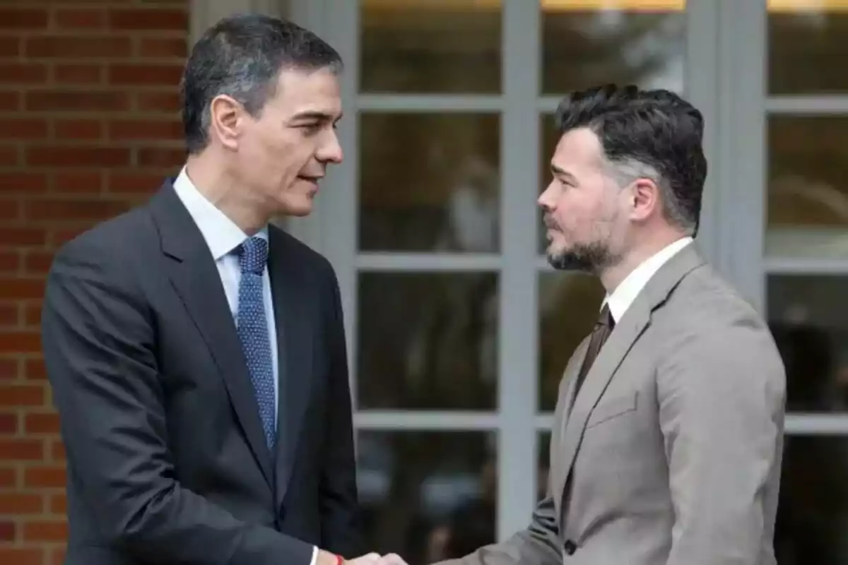 Dos hombres vestidos con traje se dan la mano y se miran frente a un edificio con paredes de ladrillo y ventanas grandes Dos hombres vestidos con traje se dan la mano y se miran frente a un edificio con paredes de ladrillo y ventanas grandes