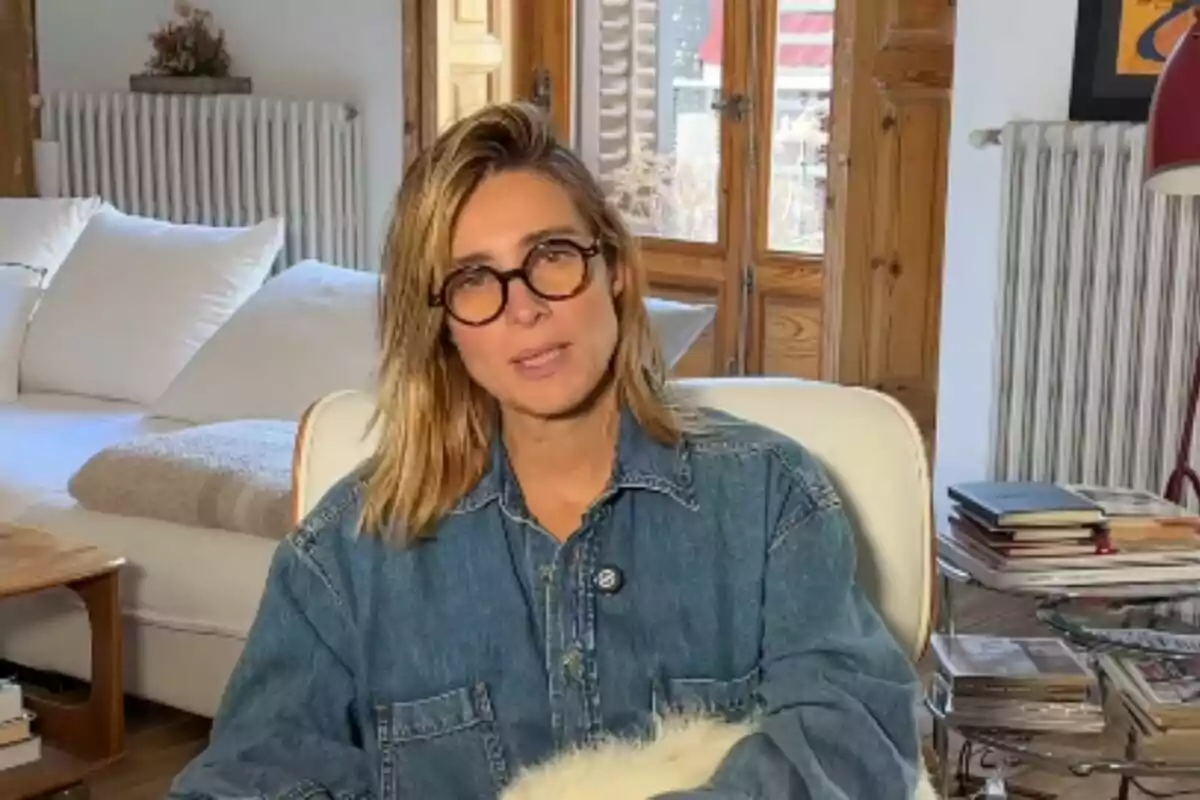 Sandra Barneda con gafas y camisa de mezclilla está sentada en una sala acogedora con muebles de madera y libros apilados. Sandra Barneda con gafas y camisa de mezclilla está sentada en una sala acogedora con muebles de madera y libros apilados.